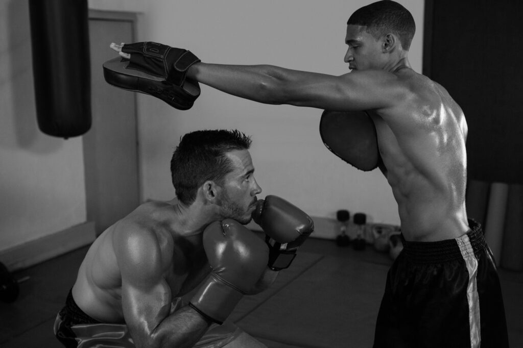 trainer assisting man in boxing wb